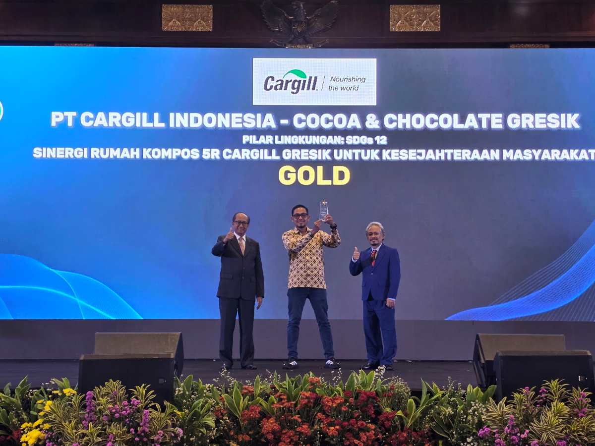 A representative from PT Cargill Indonesia – Cocoa & Chocolate Gresik holds a trophy on stage during the ISDA awards ceremony, where the company received a Gold Award for its 5R community composting initiative.